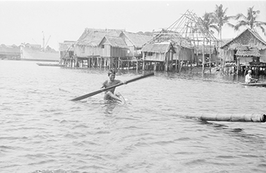 Loinclothed hobby; Obr�zek dne - the picture od the day - �awa rel - Philippines, man rowing on pole near stilt houses in Port Holland
